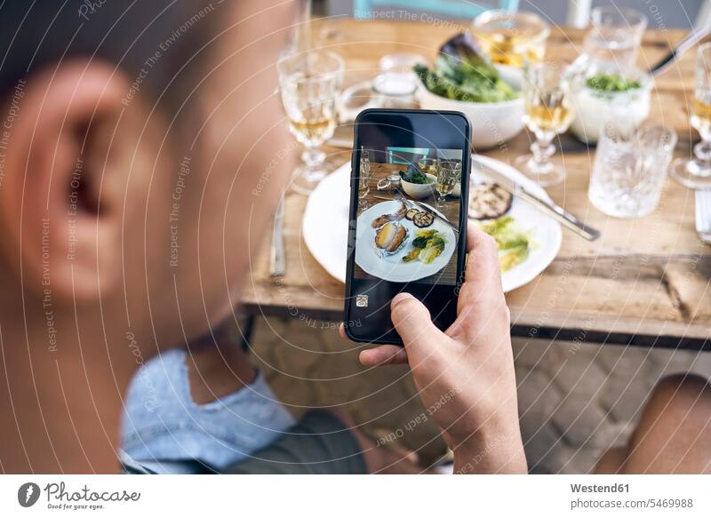 Man taking a picture of the food at a barbecue party photographing Smartphone iPhone Smartphones photographs photos Barbecue BBQ Barbeque Party Parties meat