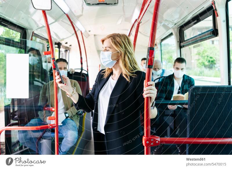 Businesswoman wearing protective mask in public bus looking at cell phone, Spain human human being human beings humans person persons caucasian appearance