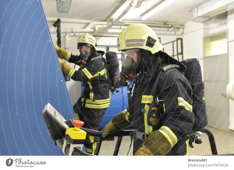 Two firefighters with respirator and air tank exercising in exercise room gym fireman air tanks Oxygen Tanks training practising espirator mask filter mask
