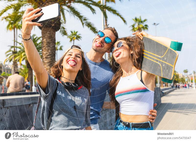 Three playful friends with skateboard taking a selfie happiness happy city town cities towns Selfie Selfies outdoors outdoor shots location shot location shots