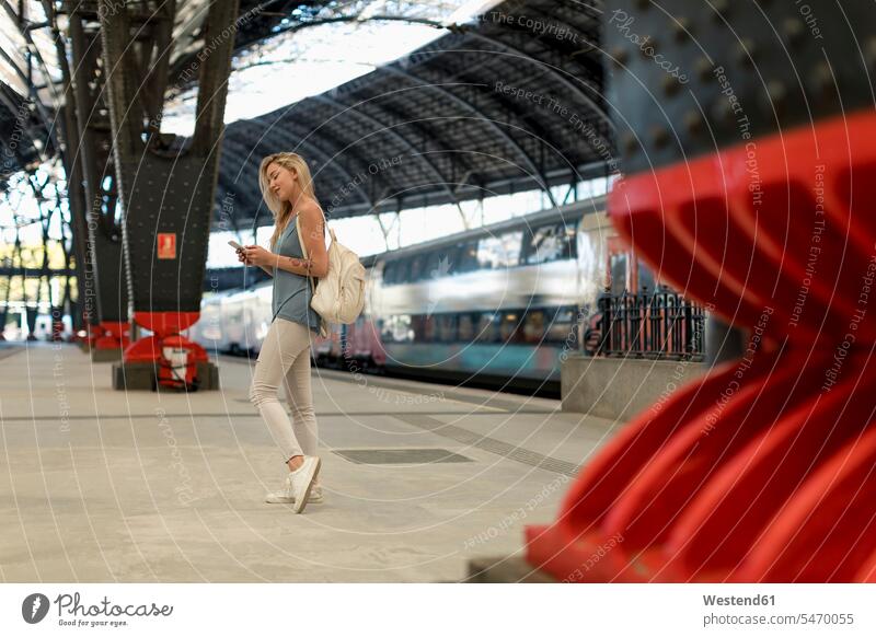 Young woman using cell phone at the train station mobile phone mobiles mobile phones Cellphone cell phones females women transportation telephones communication