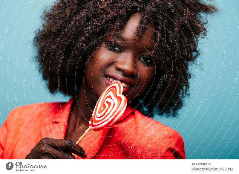 Portrait of beautiful young woman holding lollipop in studio human human being human beings humans person persons curl curled curls curly hair heads faces