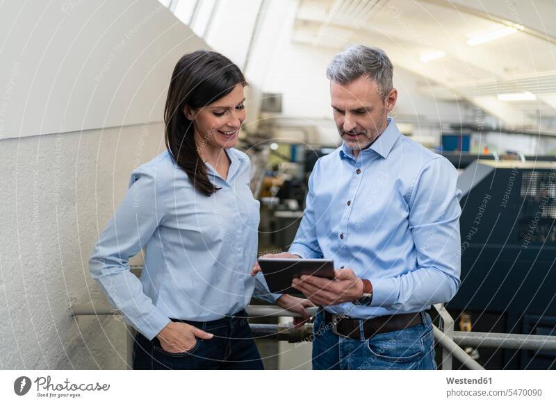 Businessman with tablet and businesswoman having a work meeting in a factory human human being human beings humans person persons caucasian appearance