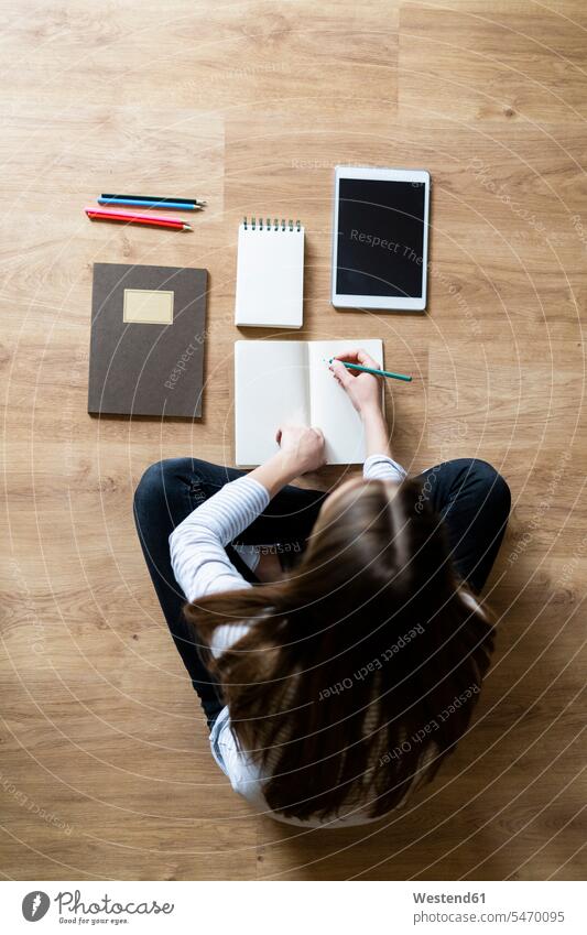 Top view of young woman sitting on the floor at home taking notes human human being human beings humans person persons celibate celibates singles