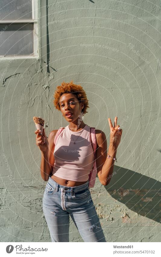 Portrait of young woman with ice cream cone posing at a wall Ice Cream Cone ice-cream cone Ice Cream Cones ice-cream wafer pose Posed portrait portraits walls