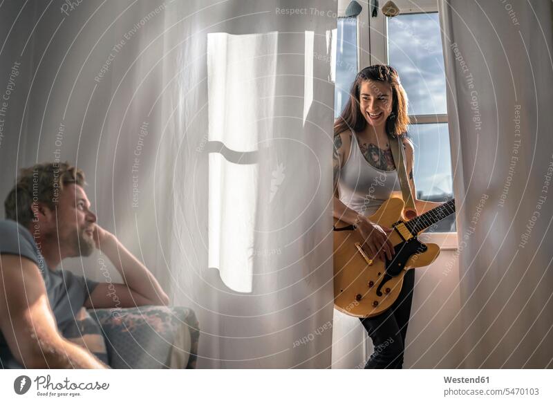 Man looking at young woman at the window at home with a guitar human human being human beings humans person persons caucasian appearance caucasian ethnicity