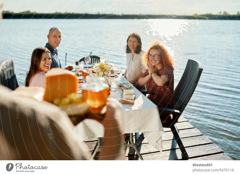 Friends having dinner at a lake with man serving cheese platter human human being human beings humans person persons caucasian appearance caucasian ethnicity
