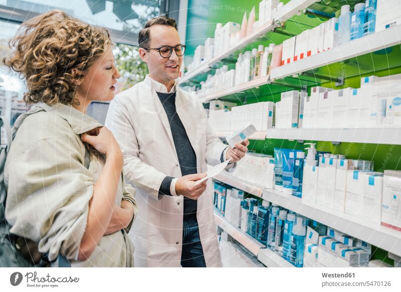 Pharmacist recommending medicine to smiling customer in chemist shop color image colour image indoors indoor shot indoor shots interior interior view Interiors