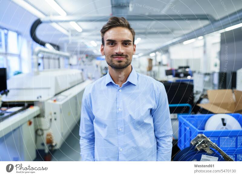 Smiling young male professional standing at illuminated factory color image colour image indoors indoor shot indoor shots interior interior view Interiors