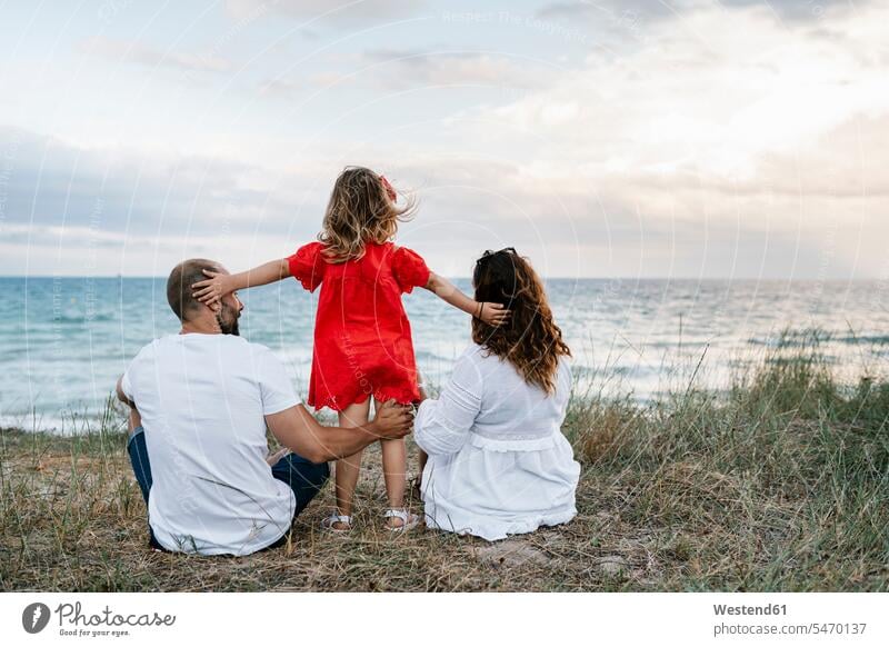 Family spending quality time at beach against cloudy sky color image colour image outdoors location shots outdoor shot outdoor shots day daylight shot