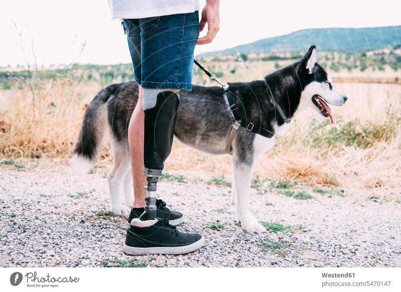 Young man wearing leg prosthesis with dog on dirt track human human being human beings humans person persons caucasian appearance caucasian ethnicity european 1