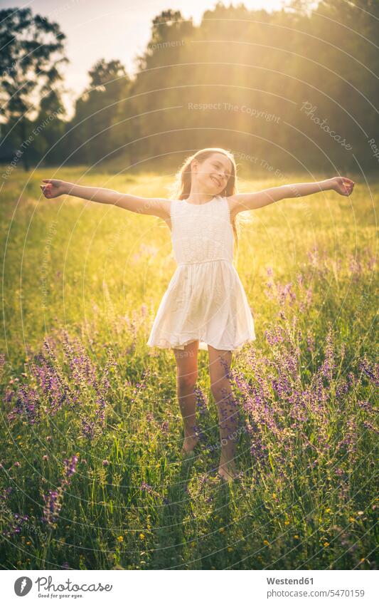 Happy girl dancing on flower meadow at evening twilight happiness happy females girls dance evening light child children kid kids people persons human being