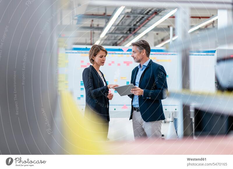 Businessman and businesswoman talking in a factory hall human human being human beings humans person persons caucasian appearance caucasian ethnicity european 2