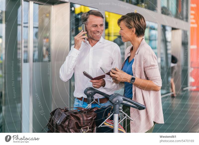 Smiling couple holding passports at the airport baggage cart luggage cart baggage carts luggage carts twosomes partnership couples smiling smile terminal