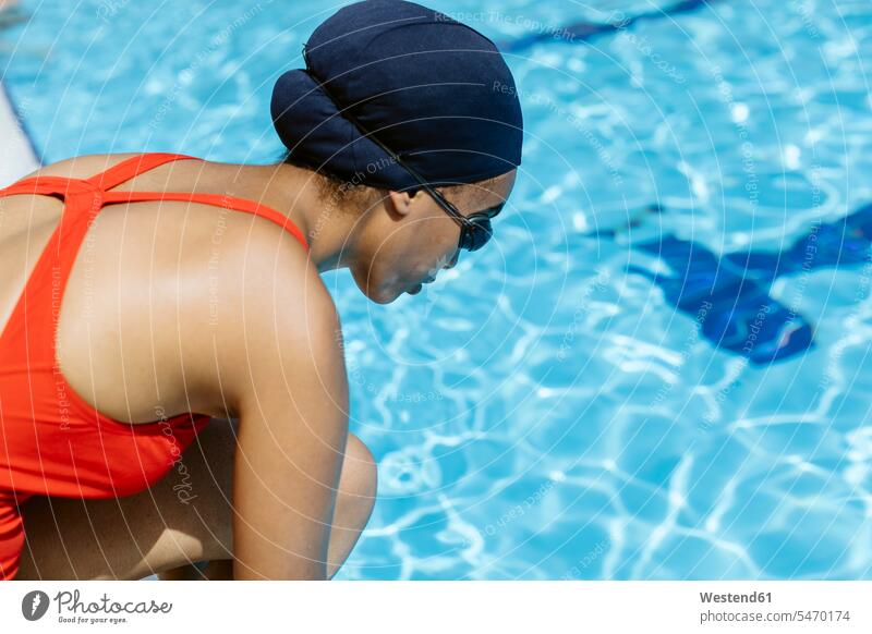 Young woman wearing swimming cap and goggles at poolside human human being human beings humans person persons African black black ethnicity coloured