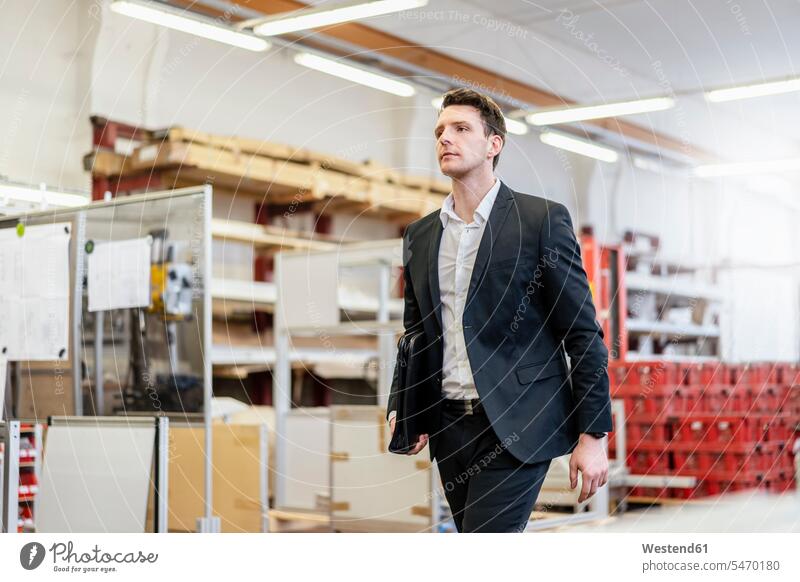 Businessman walking in a factory Business man Businessmen Business men factories going males business people businesspeople business world business life Adults