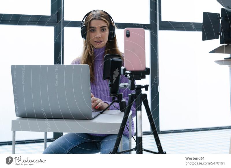 Portrait of young woman recording with laptop and smartphone in a studio human human being human beings humans person persons caucasian appearance