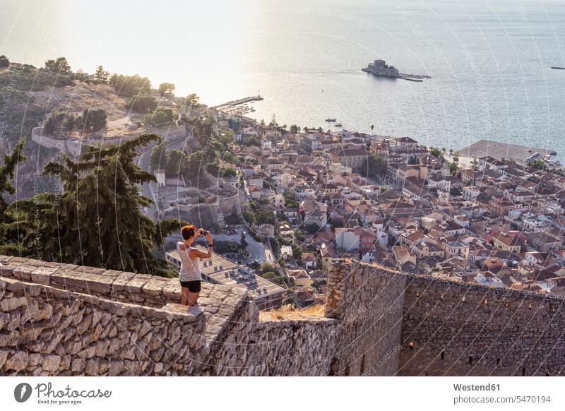 Greece, Peloponnese, Argolis, Nauplia, Argolic Gulf, woman photographing view to Bourtzi Castle Traveller Travellers Travelers taking a photo Taking Photos