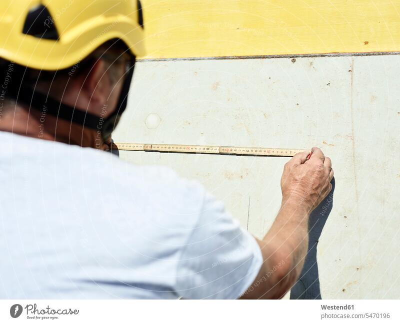 Construction worker using folding ruler and pencil on concrete wall construction site Building Site sites Building Sites construction sites construction worker