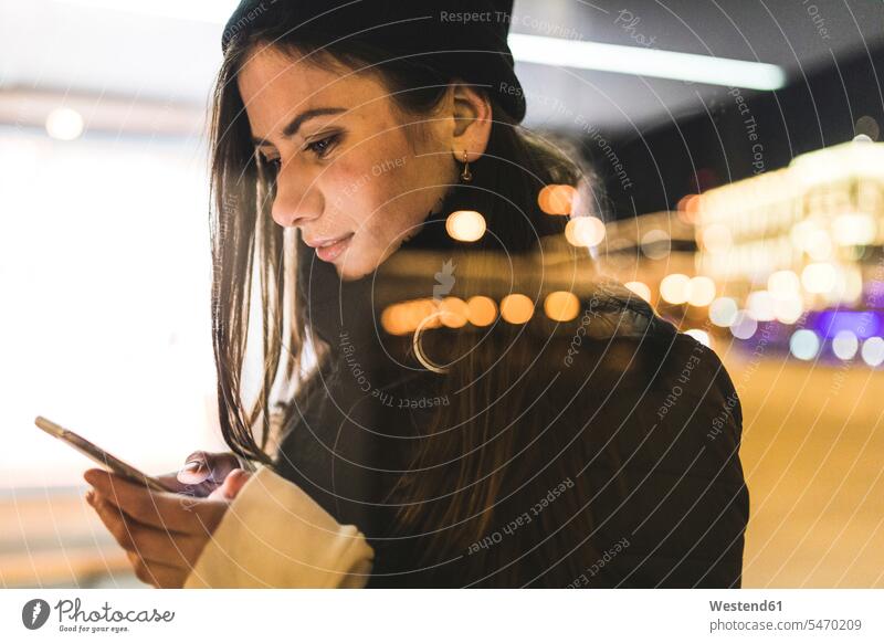 Russia, Moscow, woman in the city at night looking at smartphone by night nite night photography females women town cities towns mobile phone mobiles