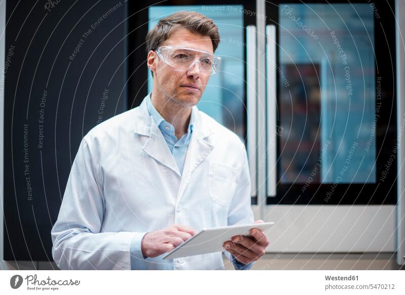 Portrait of man wearing lab coat and safety goggles holding tablet at machine men males digitizer Tablet Computer Tablet PC Tablet Computers iPad Digital Tablet
