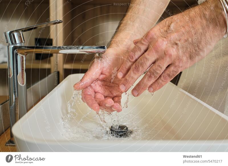 Mature man washing hands in running water in bathroom at home color image colour image indoors indoor shot indoor shots interior interior view Interiors Spain