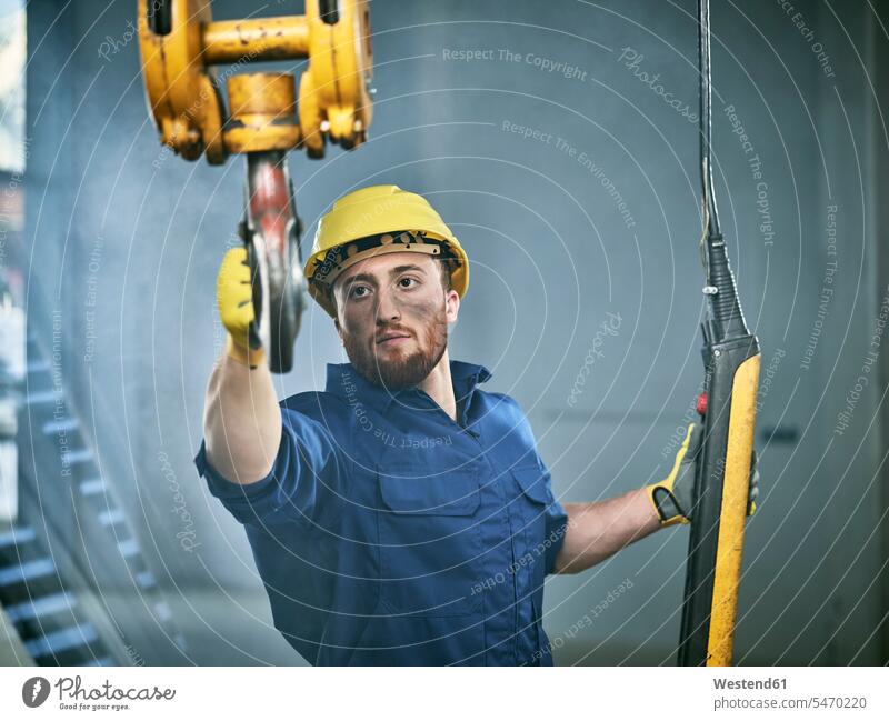 Industrial worker using hand control of indoor crane occupation profession professional occupation jobs hook hooks Safety Helmet protective helmet