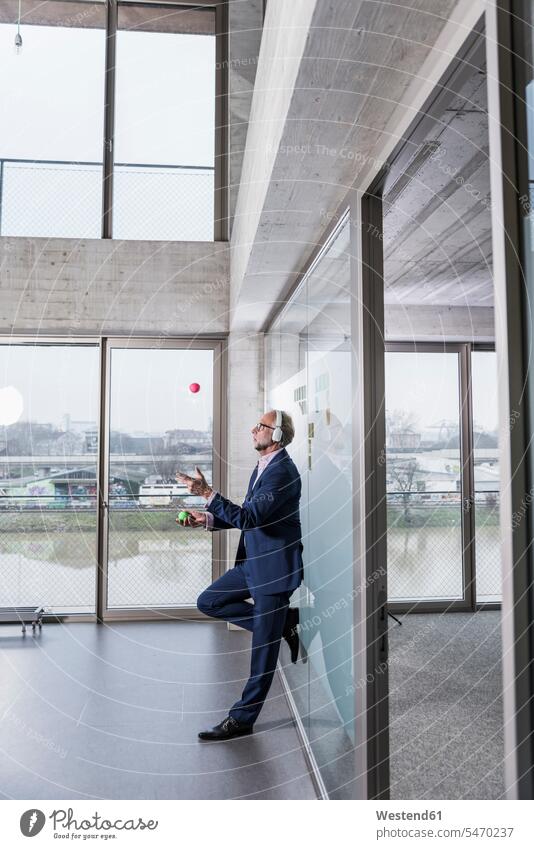 Mature businessman listening to music on headphones juggling with balls hearing Businessman Business man Businessmen Business men headset juggle business people