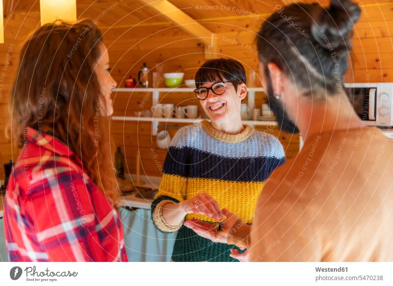 Host welcoming young couple in a cabin in the countryside handing over house key touristic tourists human human being human beings humans person persons curl