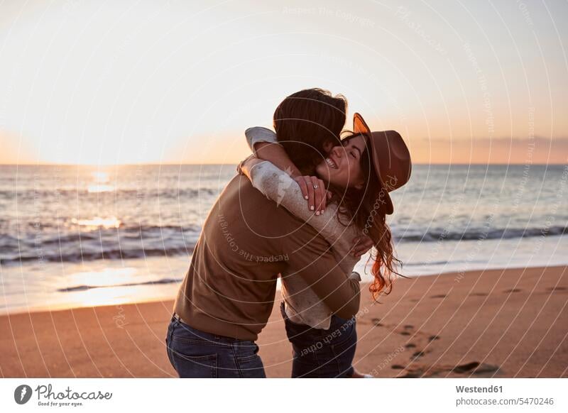 Young couple embracing each other while standing at beach color image colour image outdoors location shots outdoor shot outdoor shots casual clothing