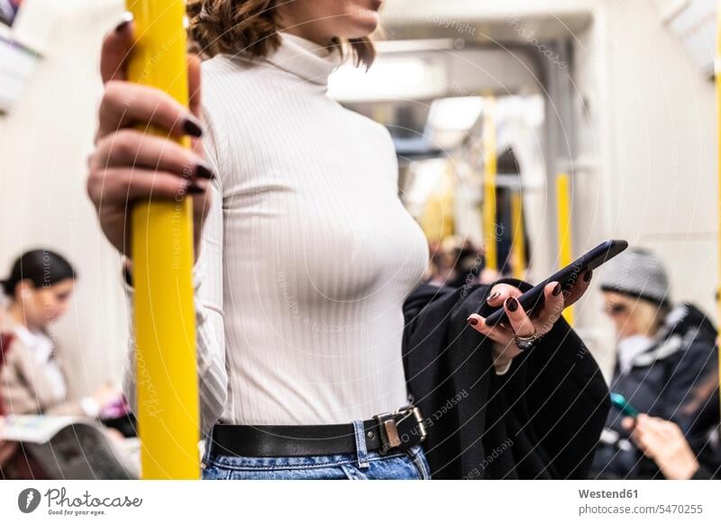 Woman commuting by train and holding mobile phone business life business world business person businesspeople business woman business women businesswomen jumper
