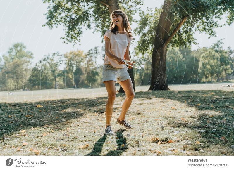 Mature woman throwing frisbee ring while standing in public park on sunny day color image colour image outdoors location shots outdoor shot outdoor shots