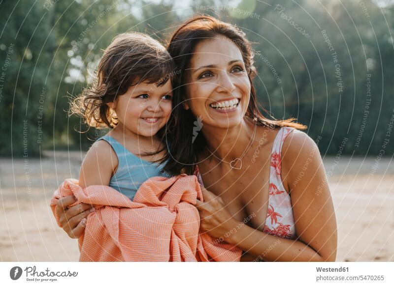 Smiling mother putting towel around her daughter at beach color image colour image outdoors location shots outdoor shot outdoor shots day daylight shot