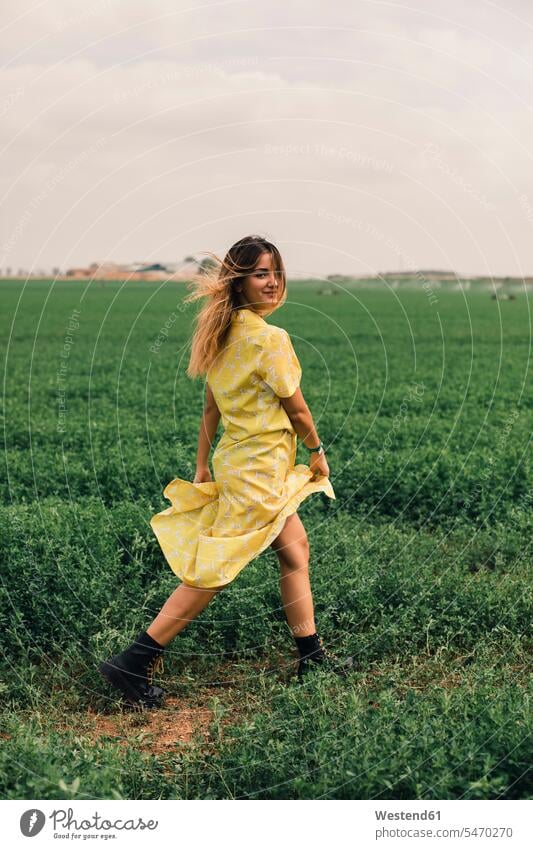 Young woman walking in a green field looking at camera looking to camera looking at the camera Eye Contact summer summer time summery summertime females women