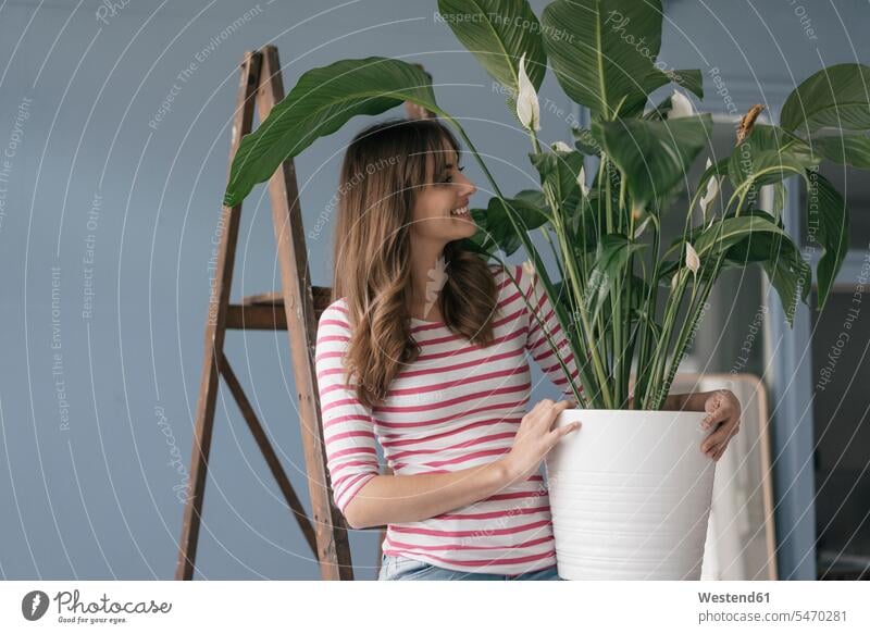Woman holding potted plant in her bew home flowerpot flowerpots flower pot flower pots woman females women at home potted plants pot  plants pot plant