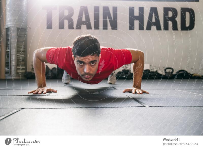 Confident male athlete practicing push-ups on floor in gym color image colour image indoors indoor shot indoor shots interior interior view Interiors gyms