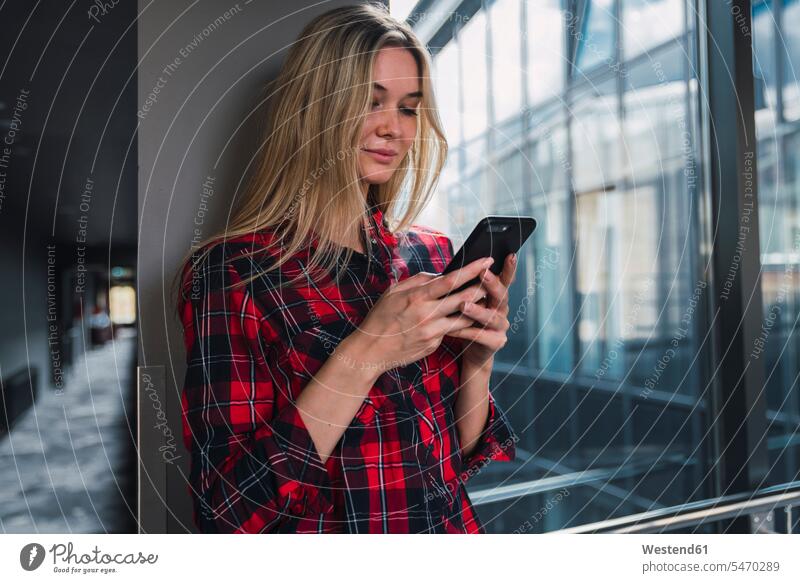 Young woman in modern office building looking at cell phone view seeing viewing office buildings females women Smartphone iPhone Smartphones built structure