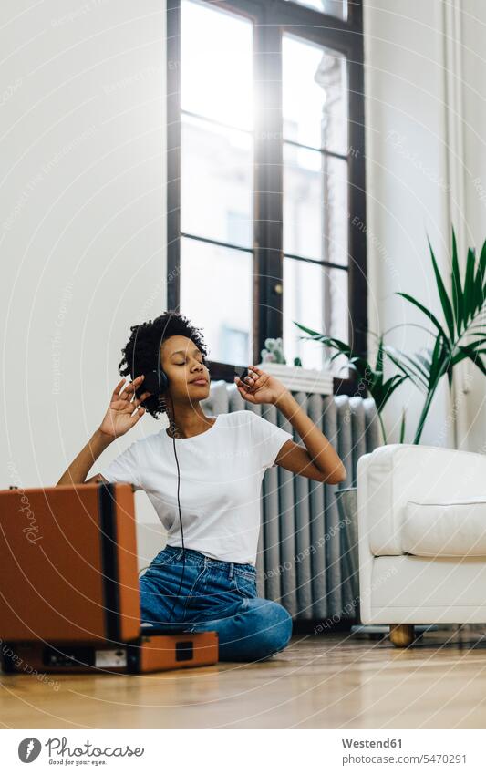 Young woman sitting on grounf listening music from record player, using headphones sitting on ground Sitting On The Floor Sitting On Floor turntable