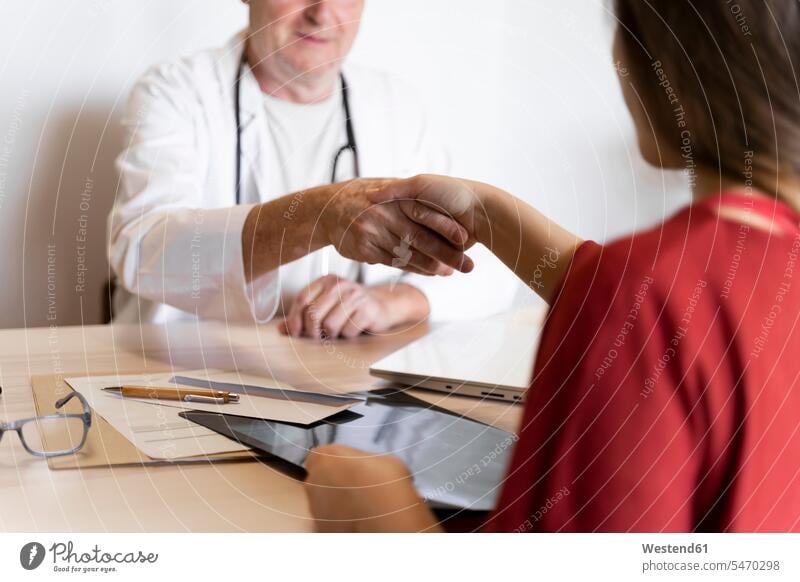 Doctor shaking hand with patient in clinic color image colour image indoors indoor shot indoor shots interior interior view Interiors day daylight shot
