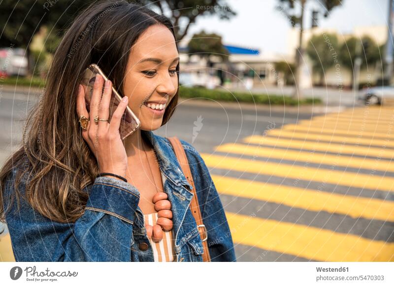 Smiling young woman talking on smartphone on the street smiling smile Smartphone iPhone Smartphones on the phone call telephoning On The Telephone calling road