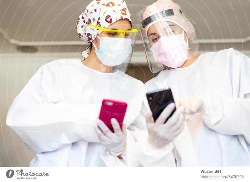 Dentist and assistant using mobile phone while standing at office color image colour image indoors indoor shot indoor shots interior interior view Interiors day