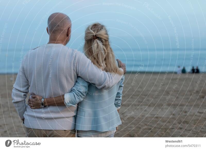 Spain, Barcelona, rear view of senior couple embracing on the beach at dusk embrace Embracement hug hugging elder couples senior couples atmosphere atmospheric