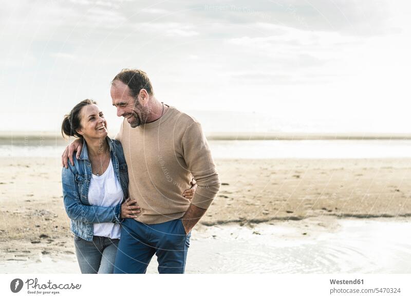Cheerful mature couple embracing while standing against sea during weekend color image colour image Netherlands Holland The Netherlands Nederland