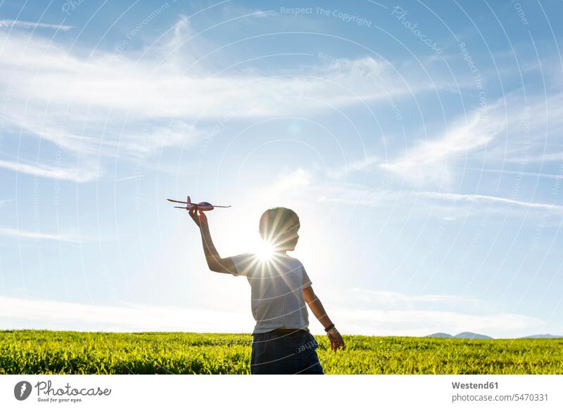Playful boy holding airplane toy while standing against clear sky color image colour image outdoors location shots outdoor shot outdoor shots day daylight shot