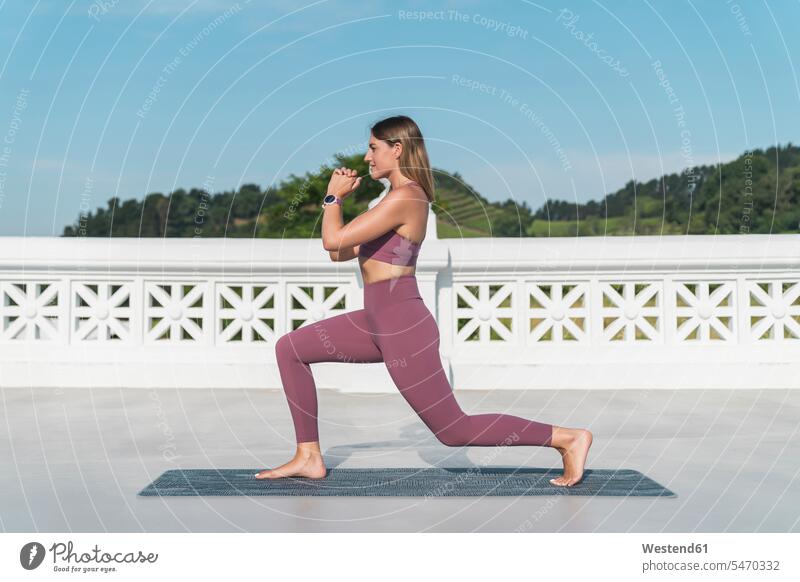 Young woman practicing yoga on building terrace against clear sky color image colour image Spain outdoors location shots outdoor shot outdoor shots day