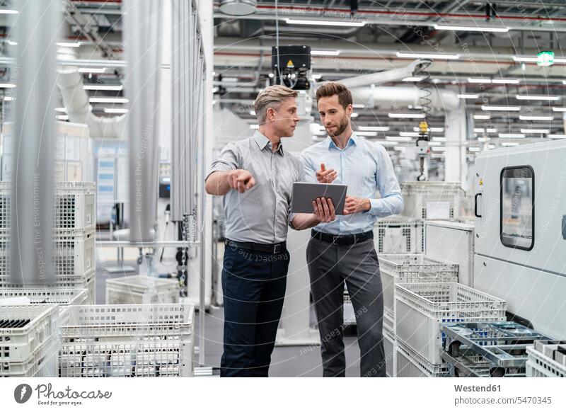Two businessmen with tablet talking in a modern factory colleague associate associates partner partners partnerships Occupation Work job jobs profession