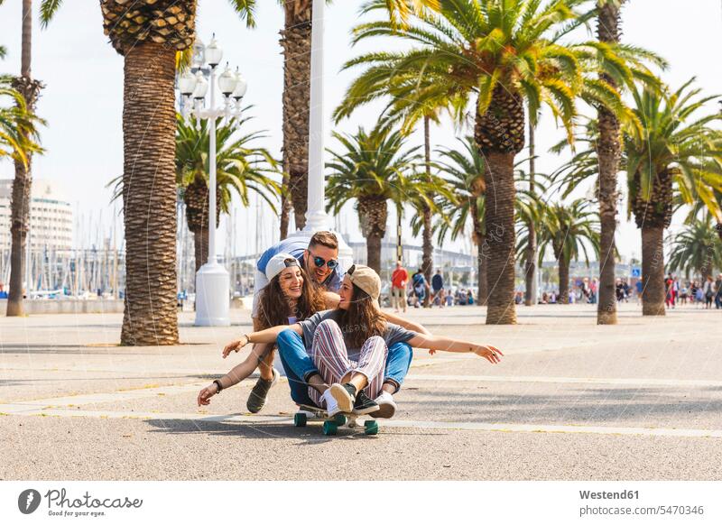 Carefree friends having fun with a skateboard on a promenade with palms carefree Palm Palm Trees Palms happiness happy promenades Skate Board skateboards Fun