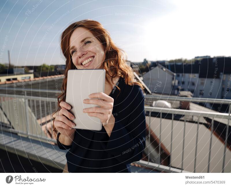 Happy redheaded woman with tablet on rooftop terrace human human being human beings humans person persons caucasian appearance caucasian ethnicity european 1