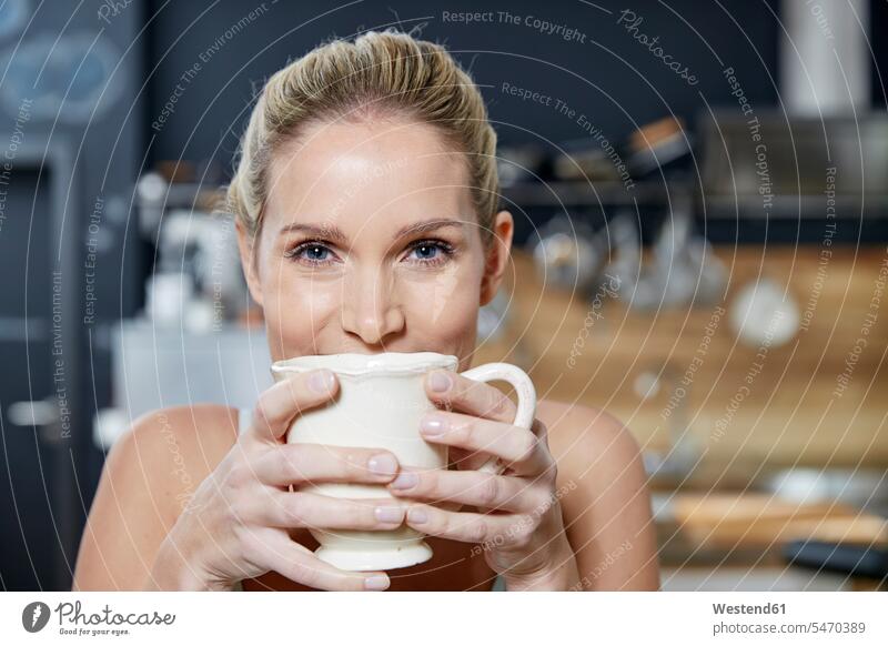 Portrait of smiling blond woman in the kitchen holding coffee mug blond hair blonde hair Coffee Mug Coffee Mugs portrait portraits females women