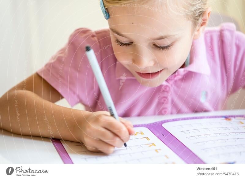 Smiling little girl writing alphabet write Alphabets females girls child children kid kids people persons human being humans human beings homework Home work